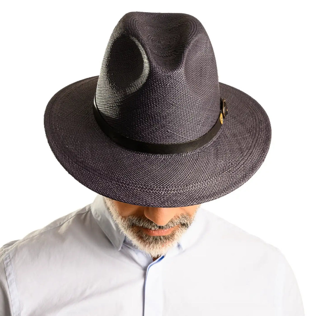 vista frontale abbassata di un uomo con barba che indossa un cappello di panama a tesa media da sole color blu fatto a mano da cappelleria primario nesti