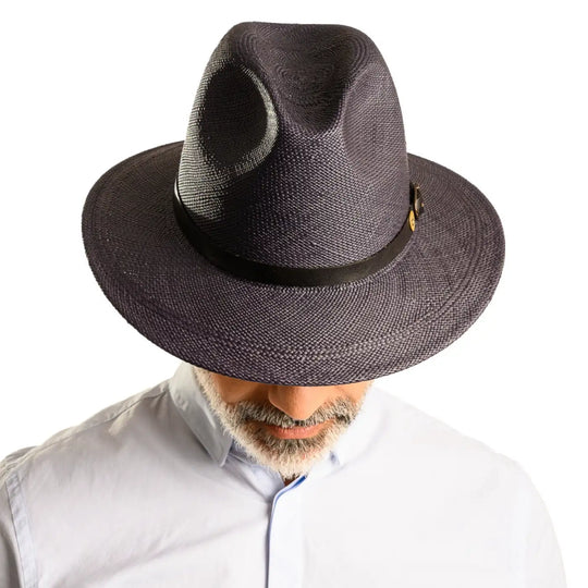 vista frontale abbassata di un uomo con barba che indossa un cappello di panama a tesa media da sole color blu fatto a mano da cappelleria primario nesti