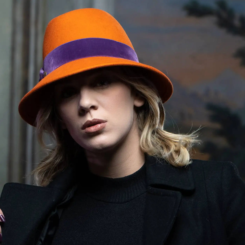 cappello a cloche con corona incavata a tesa corta primario nesti arancio modella contro muro antico design vintage contemporaneo