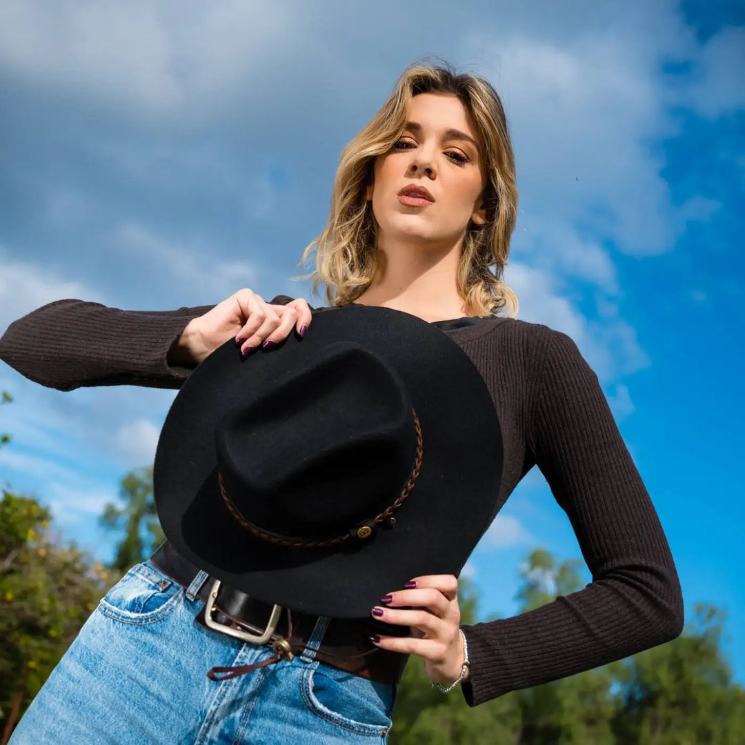 cappello da cowboy in feltro di lana merinos antipioggia primario nesti nero modella con pose dinamica cielo azzurro primaverile sullo sfondo