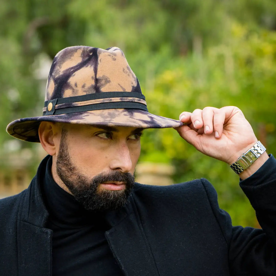 cappello fedora a tesa media in feltro di lana merinos maltinto cammello primario nesti dettaglio tesa e profilo vegetazione verde sullo sfondo