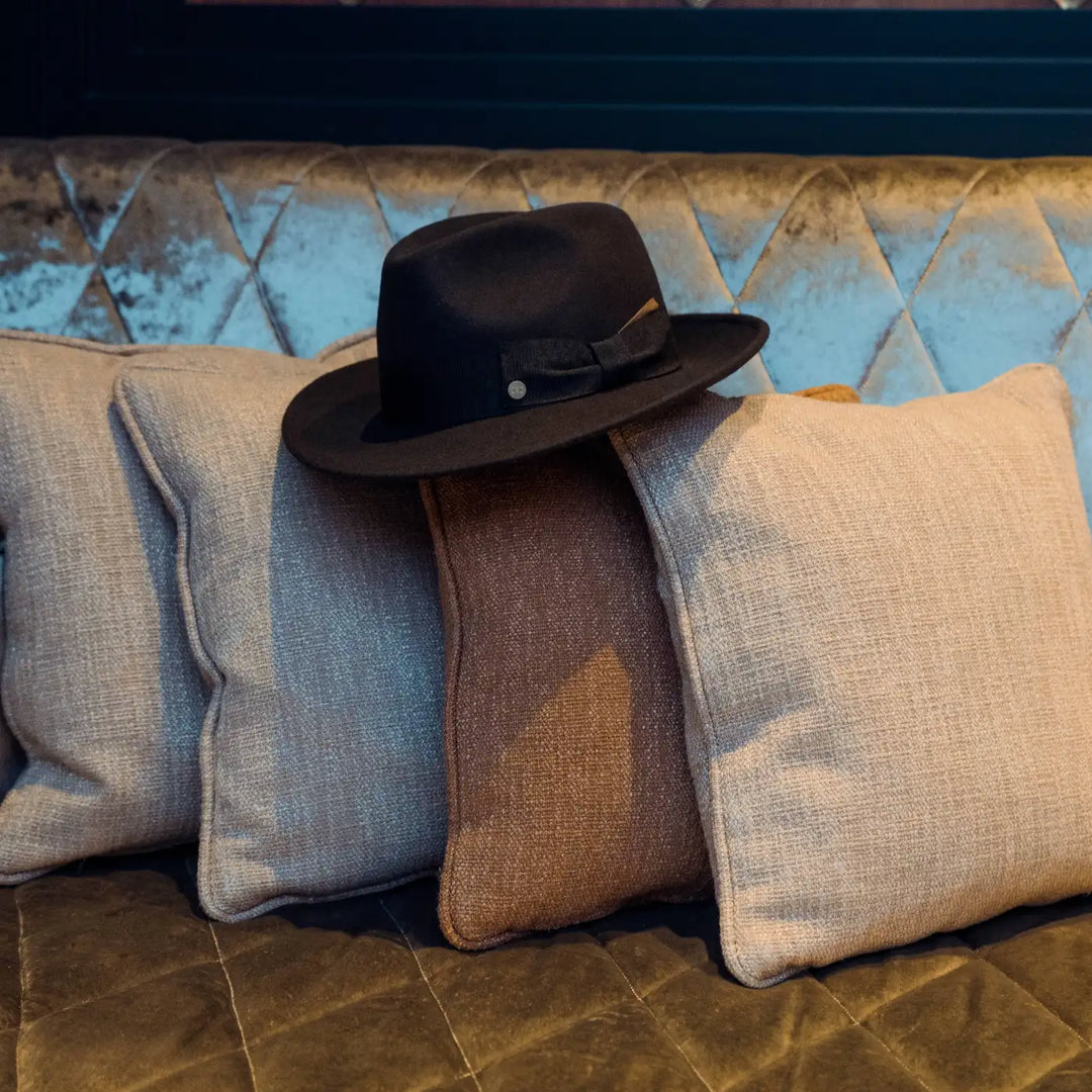 cappello fedora coccos primario nesti in lana merinos colore marrone still life su divano design e ambientazione in un luxury hotel