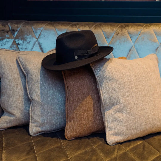 cappello fedora coccos primario nesti in lana merinos colore marrone still life su divano design e ambientazione in un luxury hotel