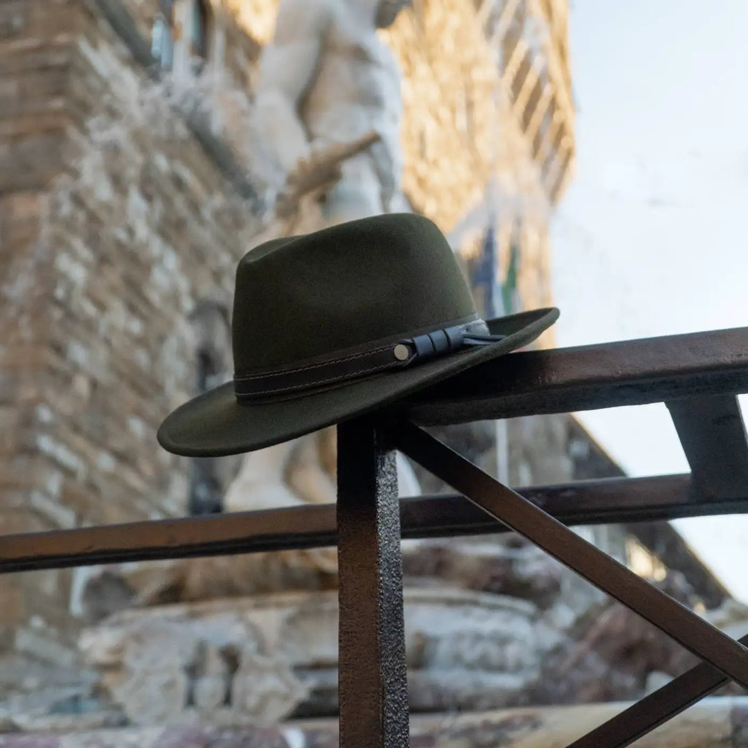 cappello fedora tradizionale primario nesti antipioggia colore verde loden esposto su ringhiera storica vero prodotto artigianale in un atmosfera vintage fiorentina