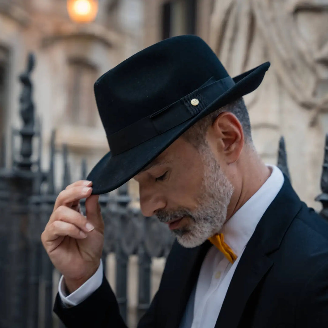 gentleman raffinato con cappello fedora primario nesti cashmere nero ritratto serale con illuminazione suggestiva