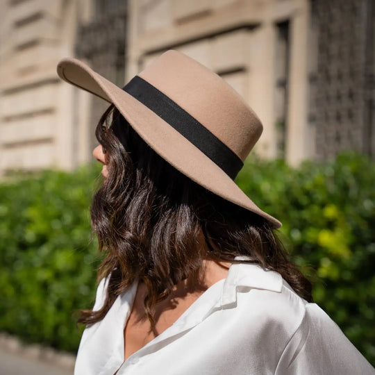 modella di profilo con cappello canotto primario nesti tesa larga piatta pose dinamica siepe verde sullo sfondo