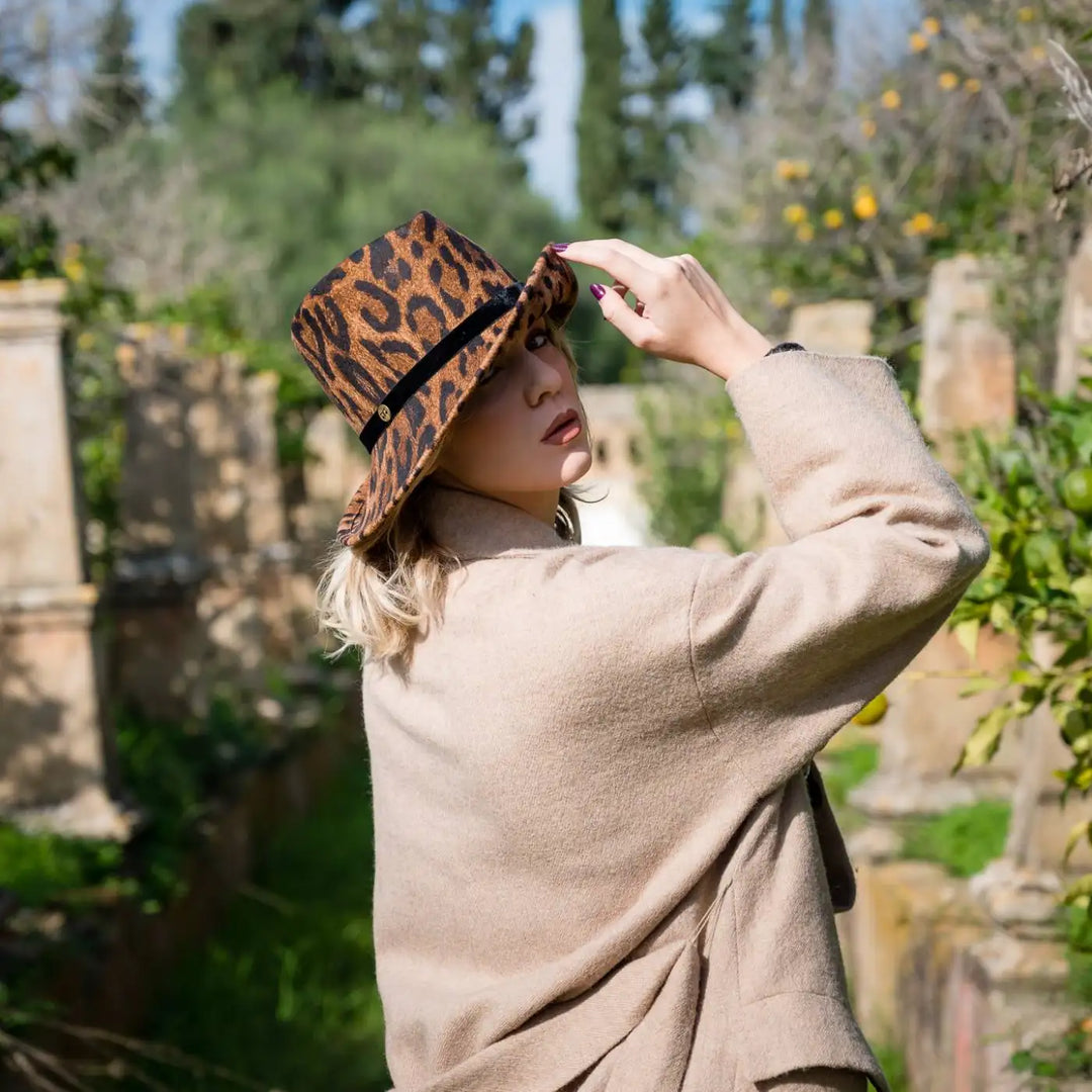 modella indossa cappello a cloche asimmetrica animalier in feltro di lana merinos primario nesti vista posteriore in giardino storico con colonne