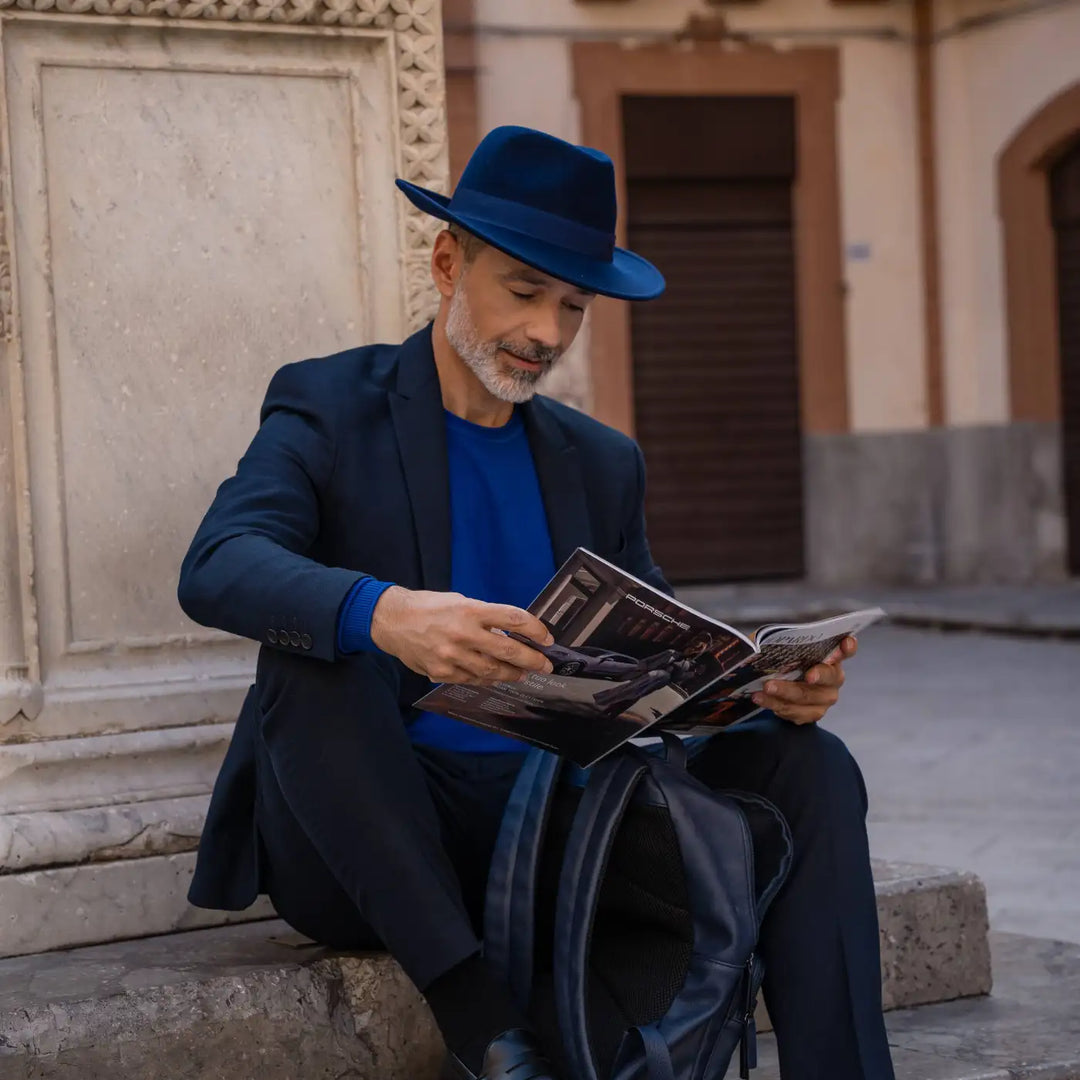 modello adulto con barba grigia indossa un cappello fedora in feltro di morbido cashmere primario nesti blu nel suo outfit navy in location depoca