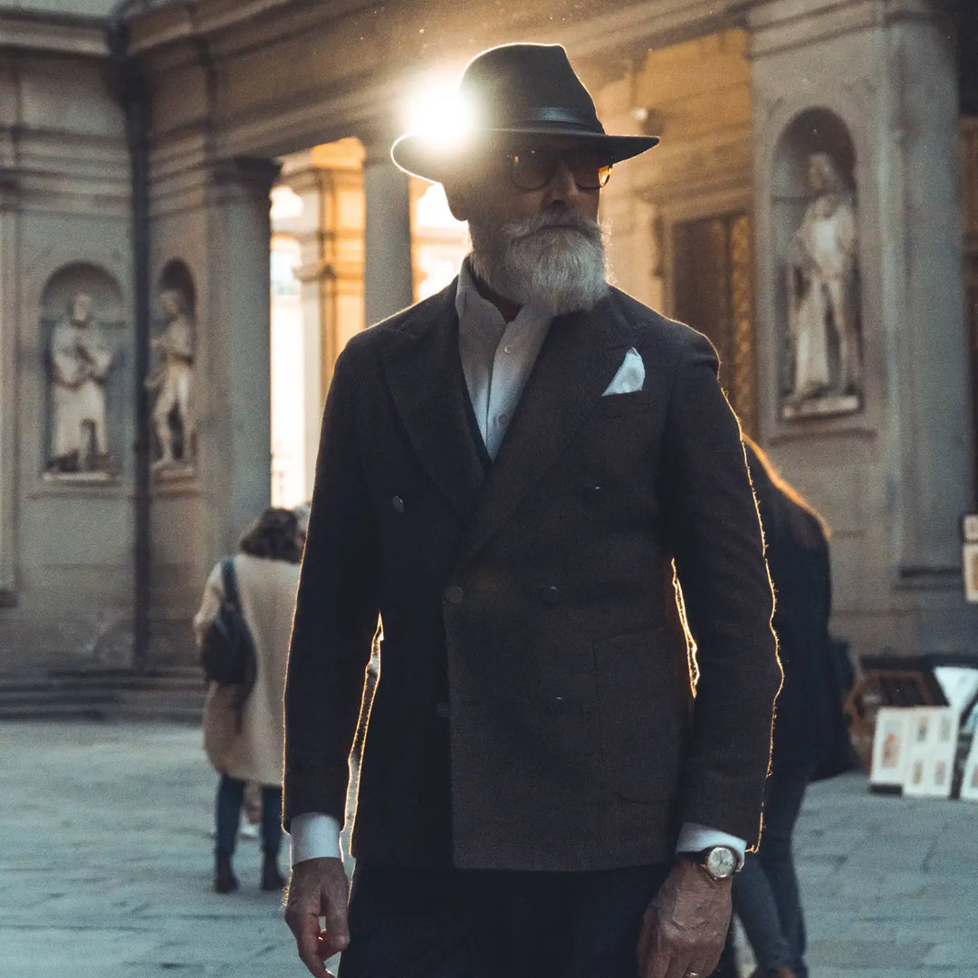 modello distinto con cappello fedora tradizionale primario nesti antipioggia colore marrone a tono con il suo completo e sfondo di portici fiorentini pe