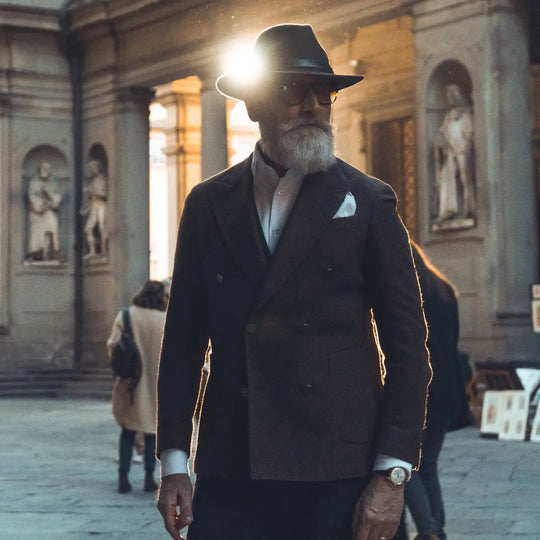 modello distinto con cappello fedora tradizionale primario nesti antipioggia colore marrone a tono con il suo completo e sfondo di portici fiorentini pe