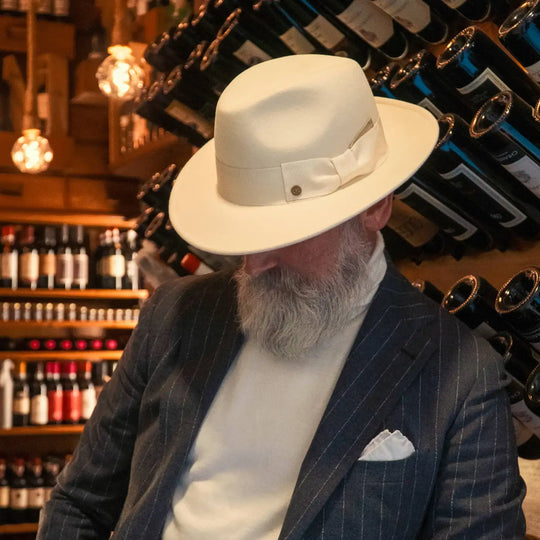 modello elegante con barba bianca e cappello fedora coccos primario nesti in lana merinos colore bianco panna nel suo look raffinato in wine bar esclusi