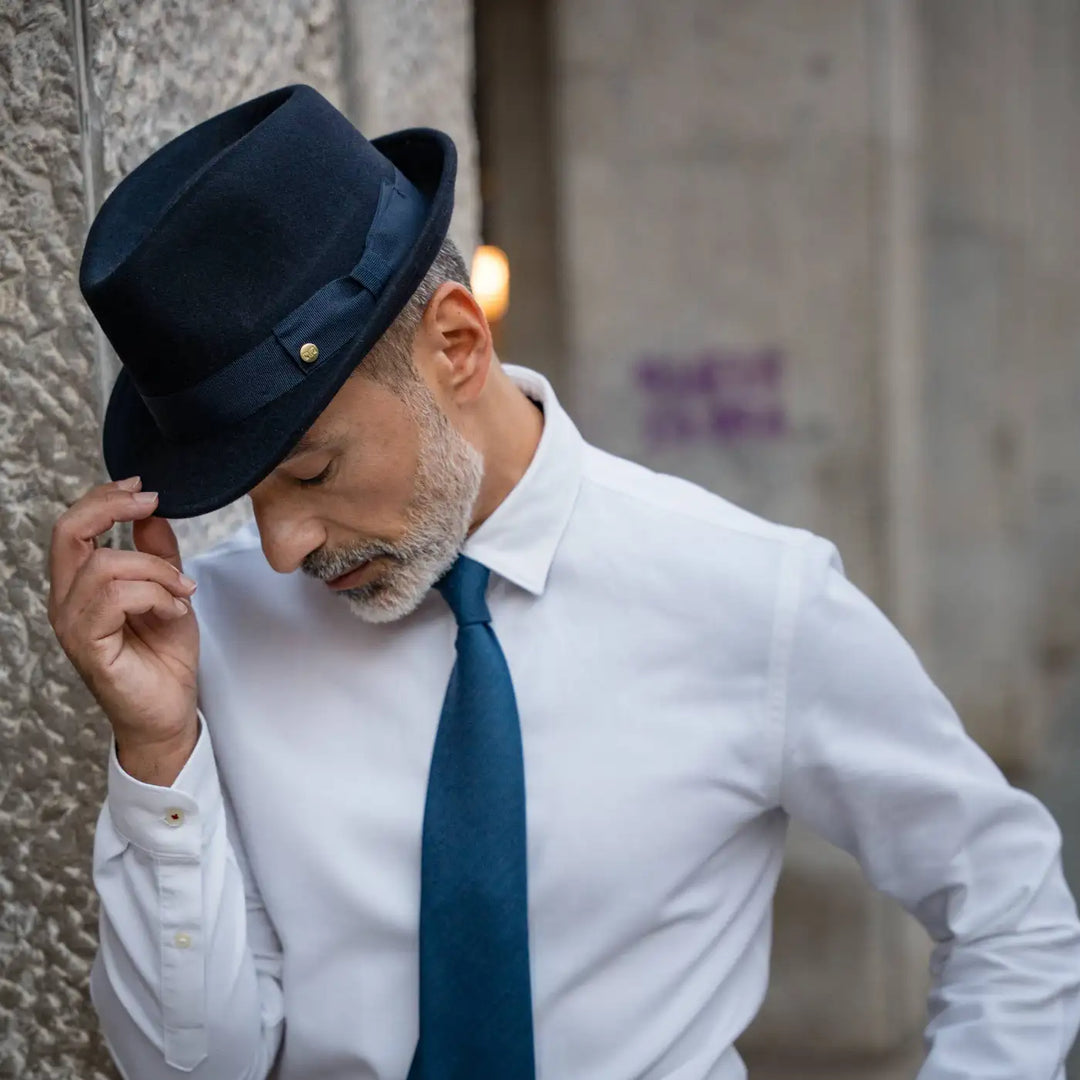 modello indossa trilby primario nesti lapin blu navy outfit formale minimalista gestualita naturale architettura storica