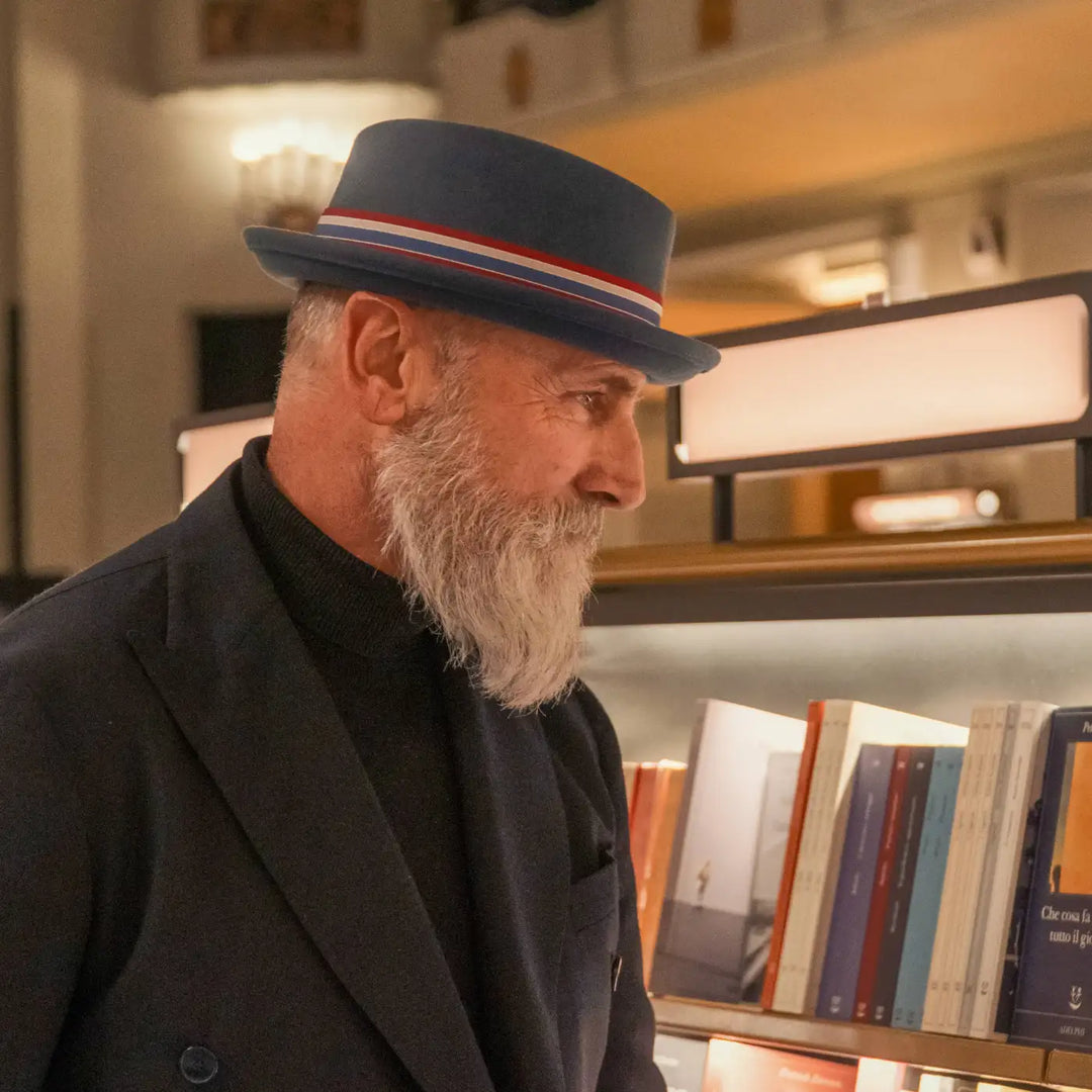 modello maturo con barba bianca e cappello pork pie primario nesti colore carta da zucchero in un momento culturale in libreria storica fiorentina