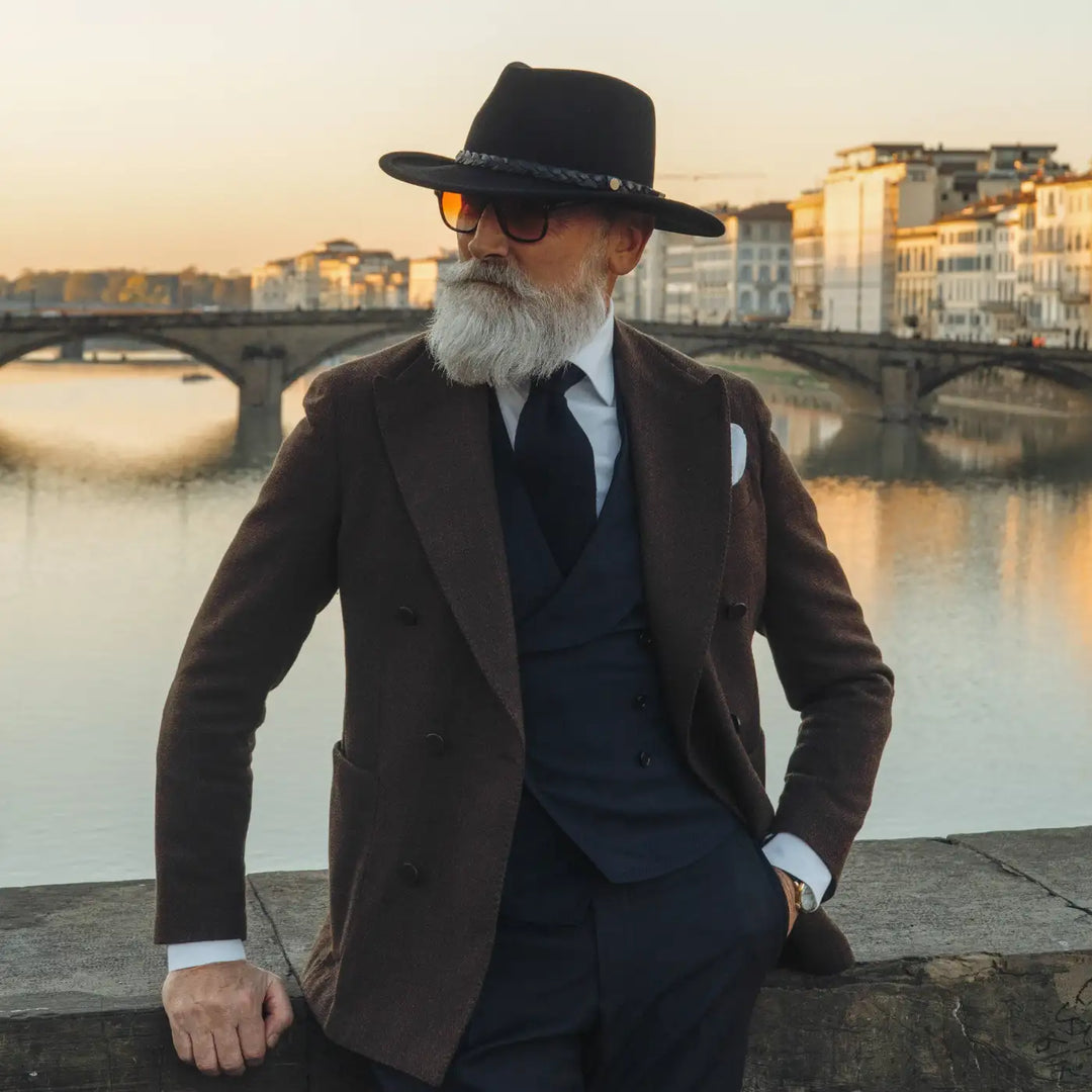 modello maturo con cappello australiano primario nesti in lana merinos marrone nel suo stile business italiano e un suggestivo panorama di firenze al crepuscolo