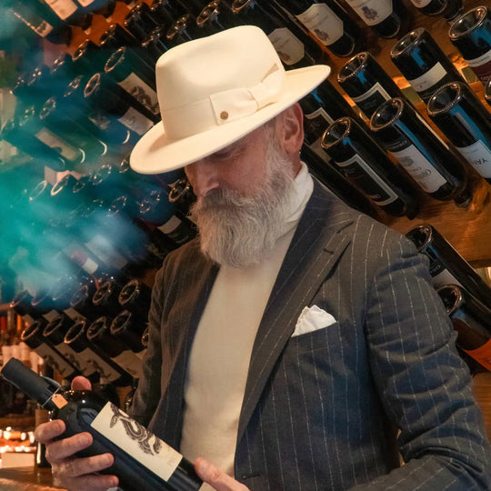 modello maturo con cappello fedora coccos primario nesti in lana merinos colore bianco panna nel suo stile contemporaneo in enoteca di lusso con illumin