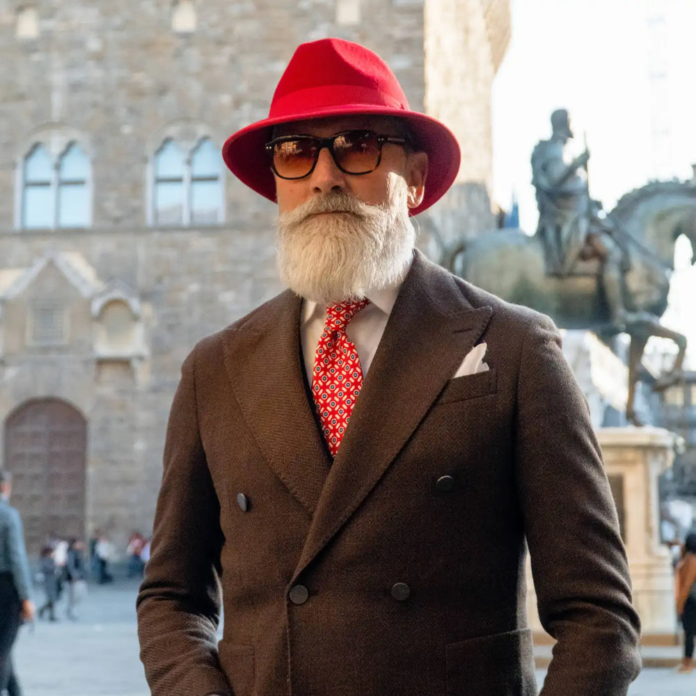 modello maturo con cappello indiana jones primario nesti in lana merinos rosso e completo marrone in piazza signoria per un eleganza italiana senza tempo