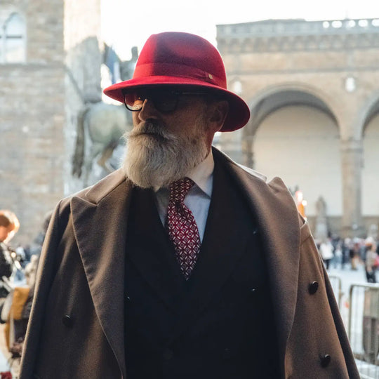 modello maturo con cappello indiana jones primario nesti in lana merinos rosso nel suo completo elegante scuro in piazza della signoria a firenze