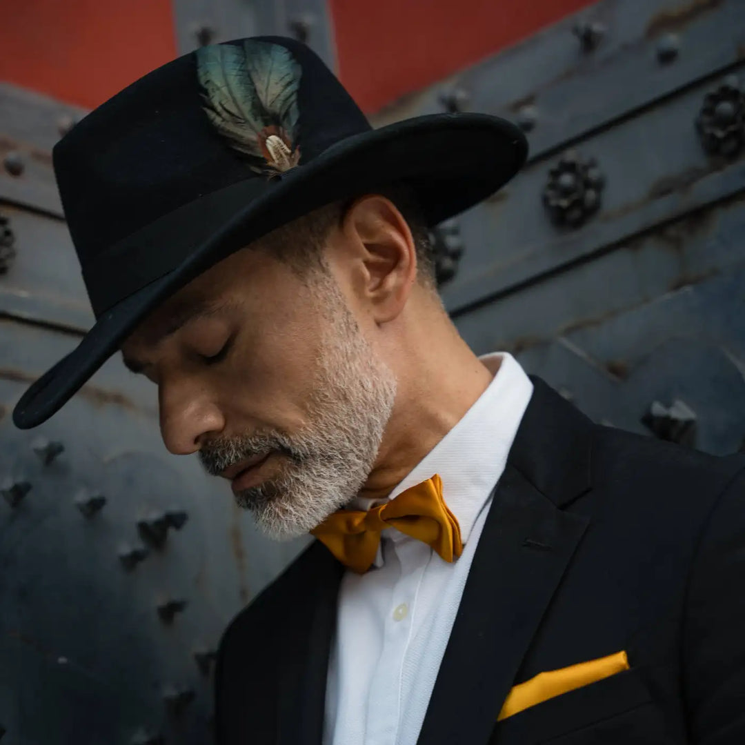 modello maturo indossa cappello australiano primario nesti cashmere nero dettaglio profilo elegante smoking raffinato con accenti arancio