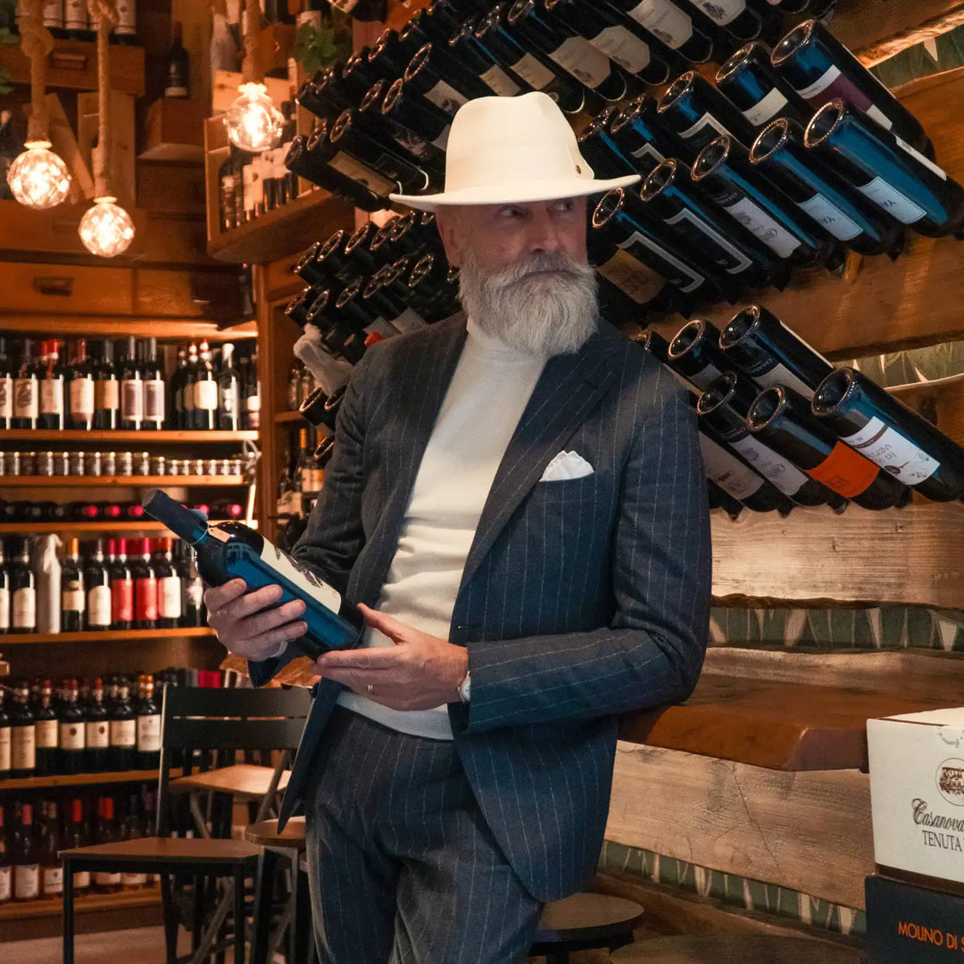 modello maturo raffinato con cappello fedora coccos primario nesti in lana merison colore bianco panna nel suo outfit business casual nellambiente sugg