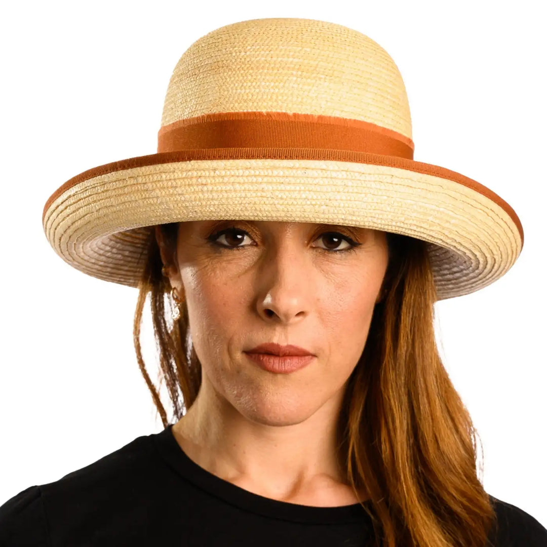 primo piano frontale di donna con capelli lunghi che indossa un cappello con fiocco in paglia di firenze color treccia chiara fatto da primario nesti