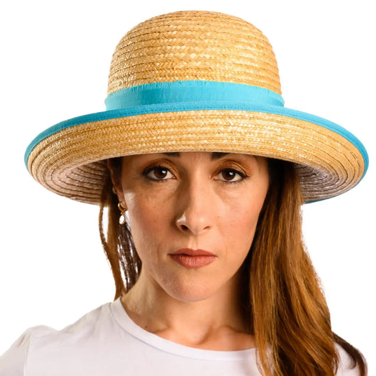primo piano frontale di donna con capelli lunghi che indossa un cappello con fiocco in paglia di firenze color treccia scura fatto da cappelleria primario nesti