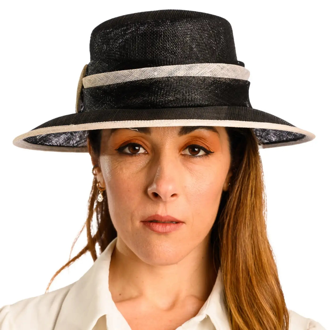 primo piano frontale di donna con capelli lunghi che indossa un cappello da cerimonia estivo elegante color nero bianco fatto da cappelleria primario nesti