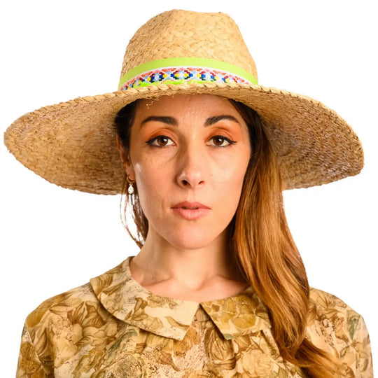 primo piano frontale di donna con capelli lunghi che indossa un cappello da mare a tesa larga in rafia color paglia lime fatto da cappelleria primario nesti