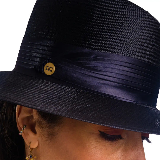 primo piano frontale ravvinato di donna con capelli lunghi che indossa un cappello tesa larga elegante in parasisol color blu fatto da primario nesti