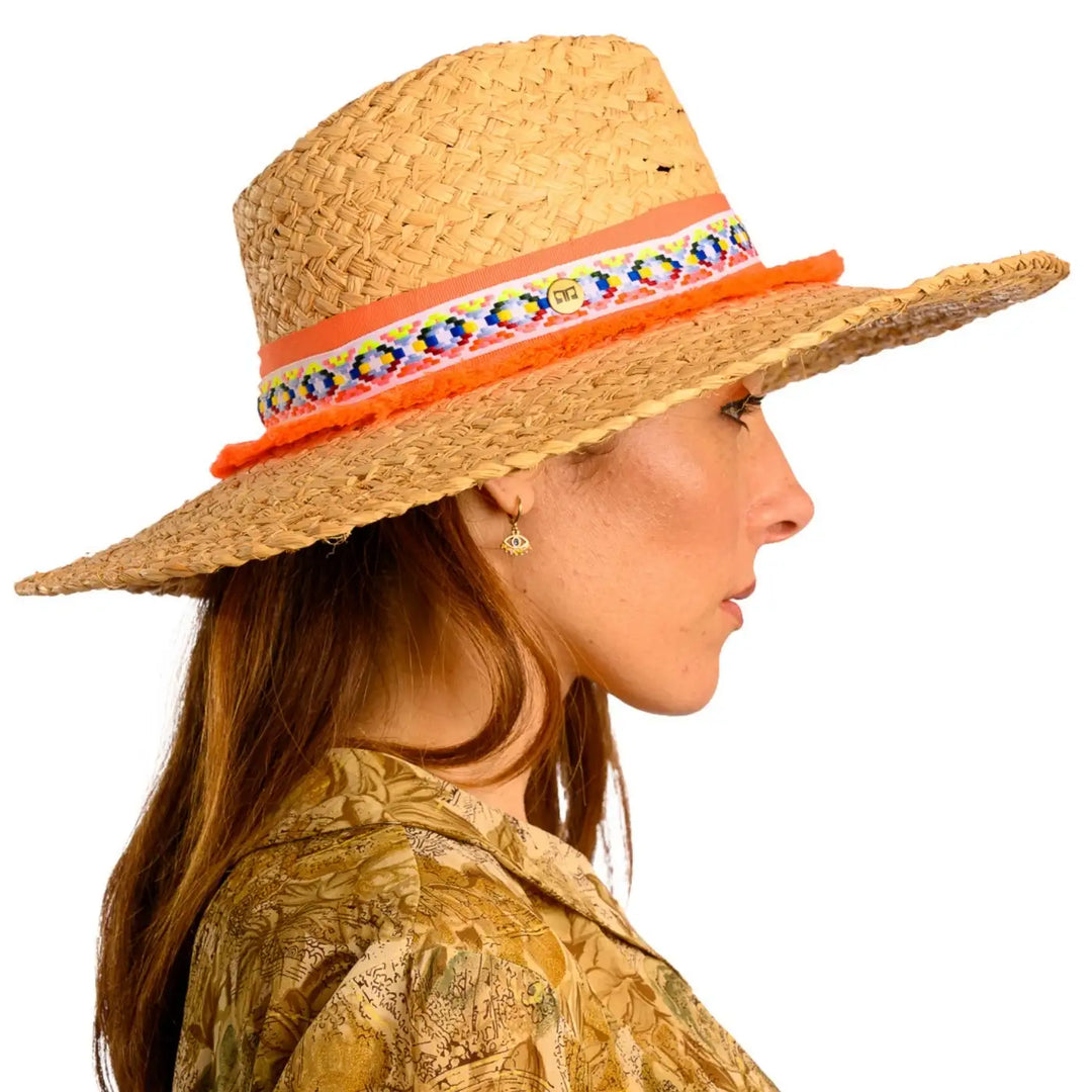 primo piano laterale di donna adulta con capelli lunghi che indossa un cappello da mare a tesa larga in rafia color paglia arancio realizzato da primario nesti