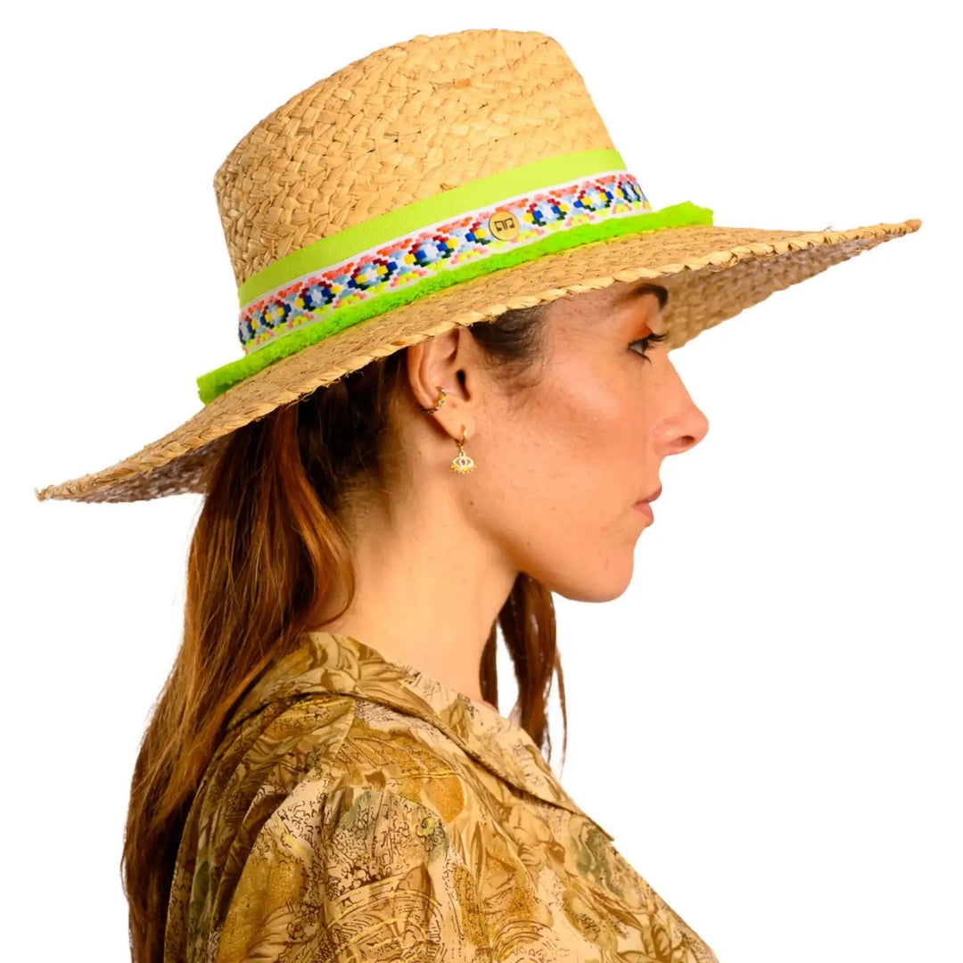 primo piano laterale di donna adulta con capelli lunghi che indossa un cappello da mare a tesa larga in rafia color paglia lime realizzato da primario nesti