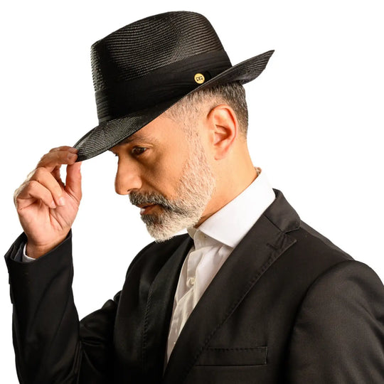 primo piano laterale inclinato di uomo con barba che indossa un cappello fedora elegante in parasisol color nero realizzato da cappelleria primario nesti
