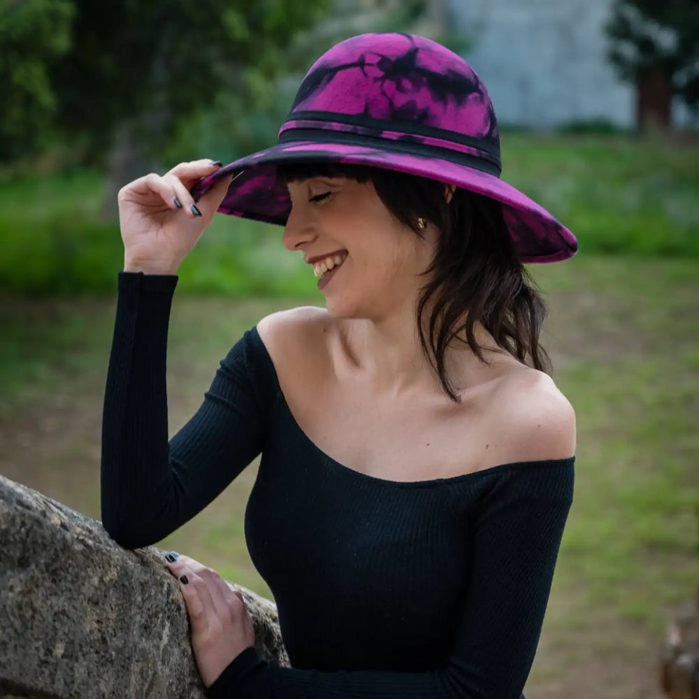 profilo di modella con risata spontanea indossa cappello a pamela a tesa larga in feltro di lana merinos maltinto primario nesti fucsia