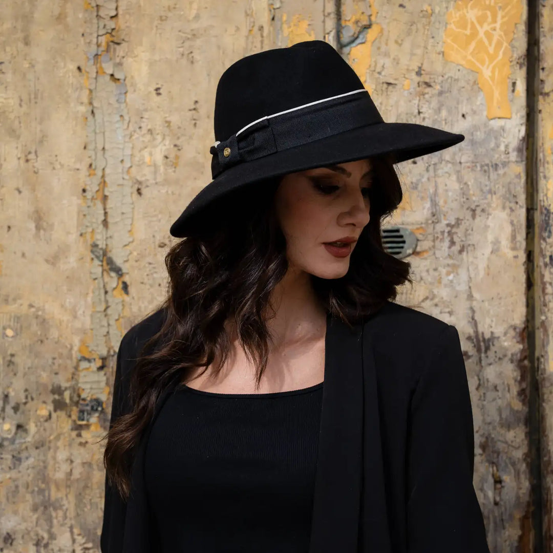 ritratto laterale di modella adulta con cappello signorile a tesa larga in feltro nero primario nesti e look femminile elegante