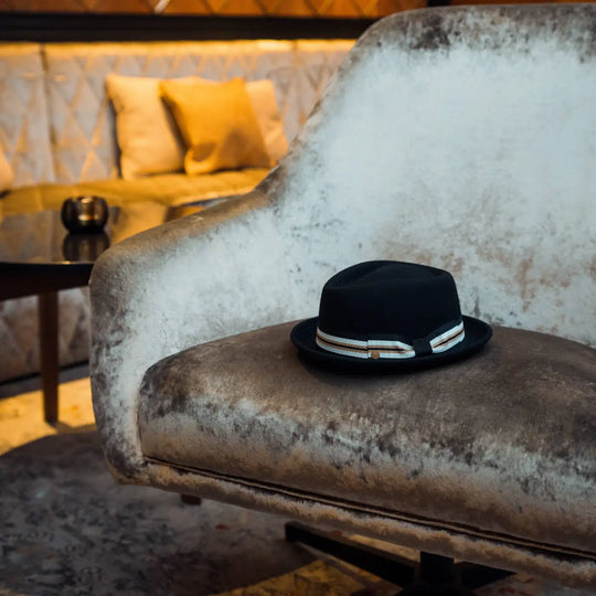 still life artistico di cappello porkpie primario nesti in lana merinos nero in un ambientazione luxury con dettagli dorati e texture design