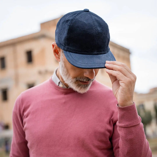 uomo elegante con berretto primario nesti velluto navy maglione bordeaux gestualita raffinata palazzo storico