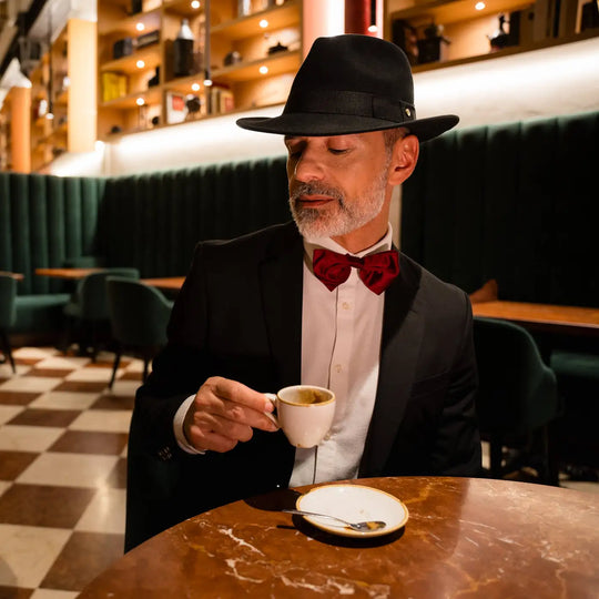 uomo raffinato con fedora primario nesti cashmere nero dettaglio tazzina caffe pavimento a scacchi caffe storico
