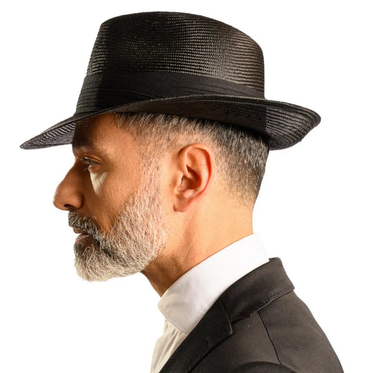 vista laterale di un uomo con barba che indossa un cappello fedora elegante in parasisol color nero fatto a mano da cappelleria primario nesti